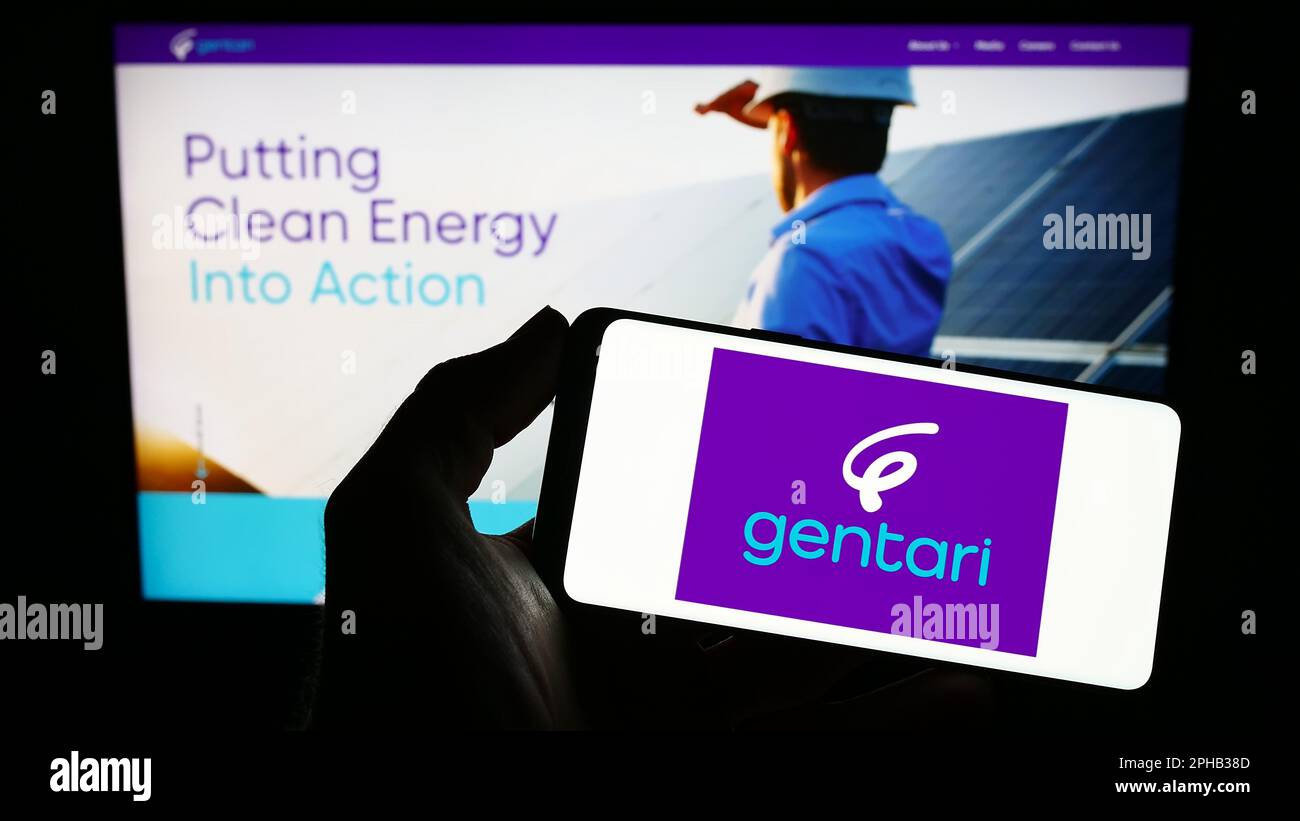 Person holding smartphone with logo of Malaysian energy company Gentari Sdn. Bhd. on screen in front of website. Focus on phone display. Stock Photo