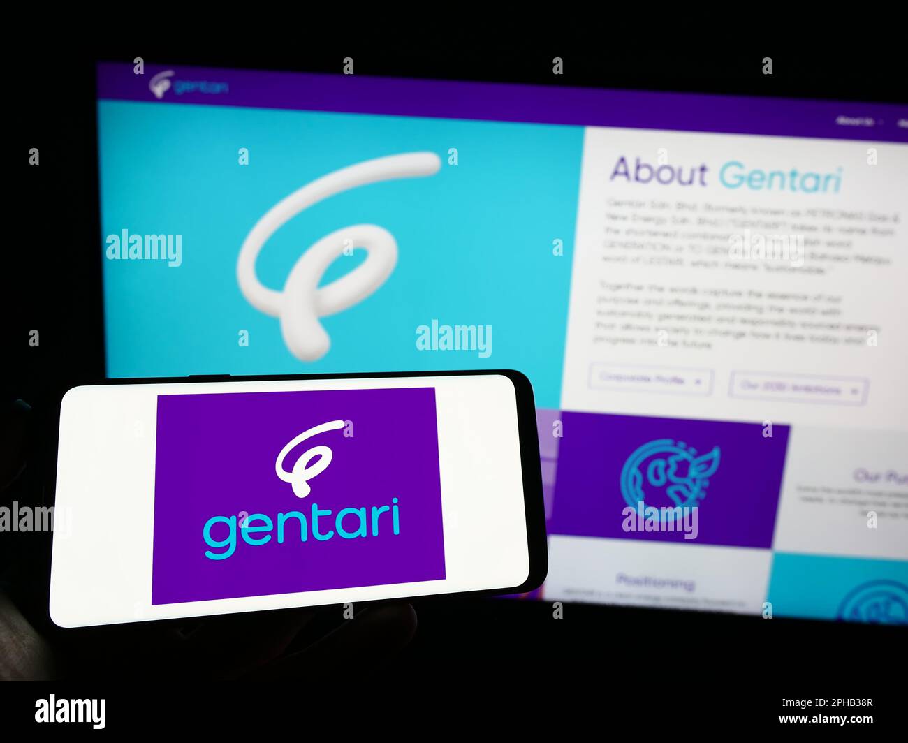 Person holding cellphone with logo of Malaysian energy company Gentari Sdn. Bhd. on screen in front of business webpage. Focus on phone display. Stock Photo