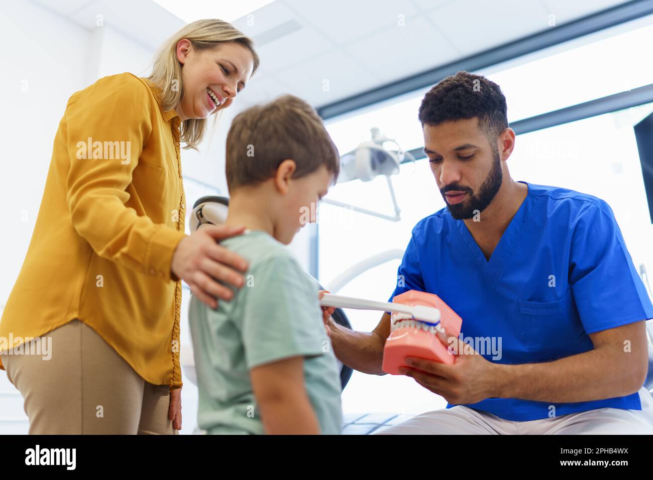 Young multiracial dentist showing little boy how to clean teeth
