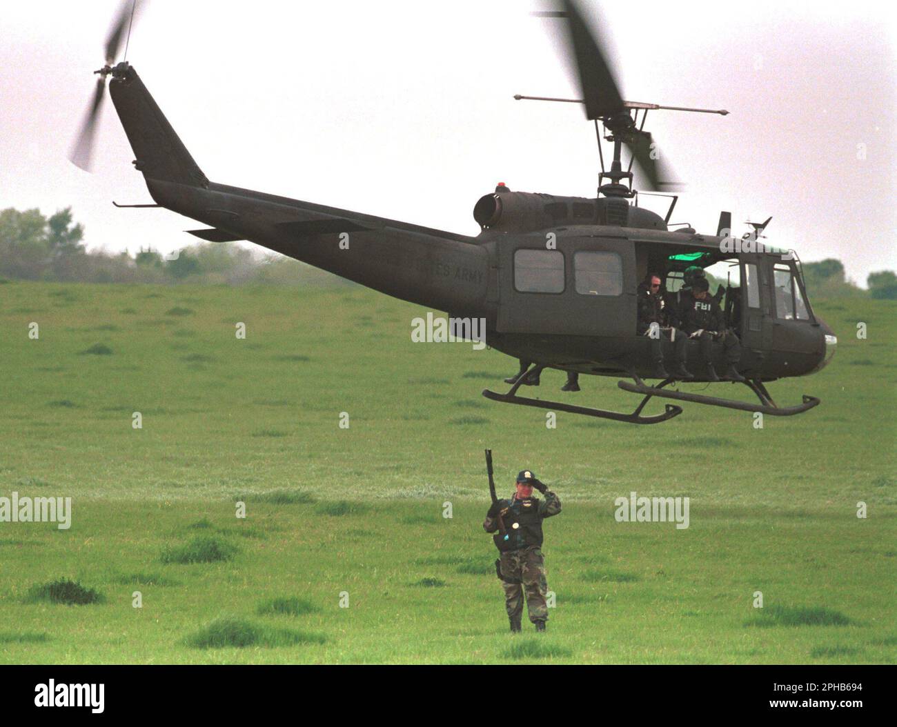 April 17, 2001: A U.S. Army helicopter with FBI agents aboard flies over a field near the Branch Davidian compound near Waco, Texas as an agent of the Alcohol Firearms and Tobacco (ATF) stands with a loaded weapon April 03, 1993 during the.standoff seven years ago. © Bob Daemmrich/ (Credit Image: © Bob Daemmrich/ZUMA Press Wire) EDITORIAL USAGE ONLY! Not for Commercial USAGE! Stock Photo