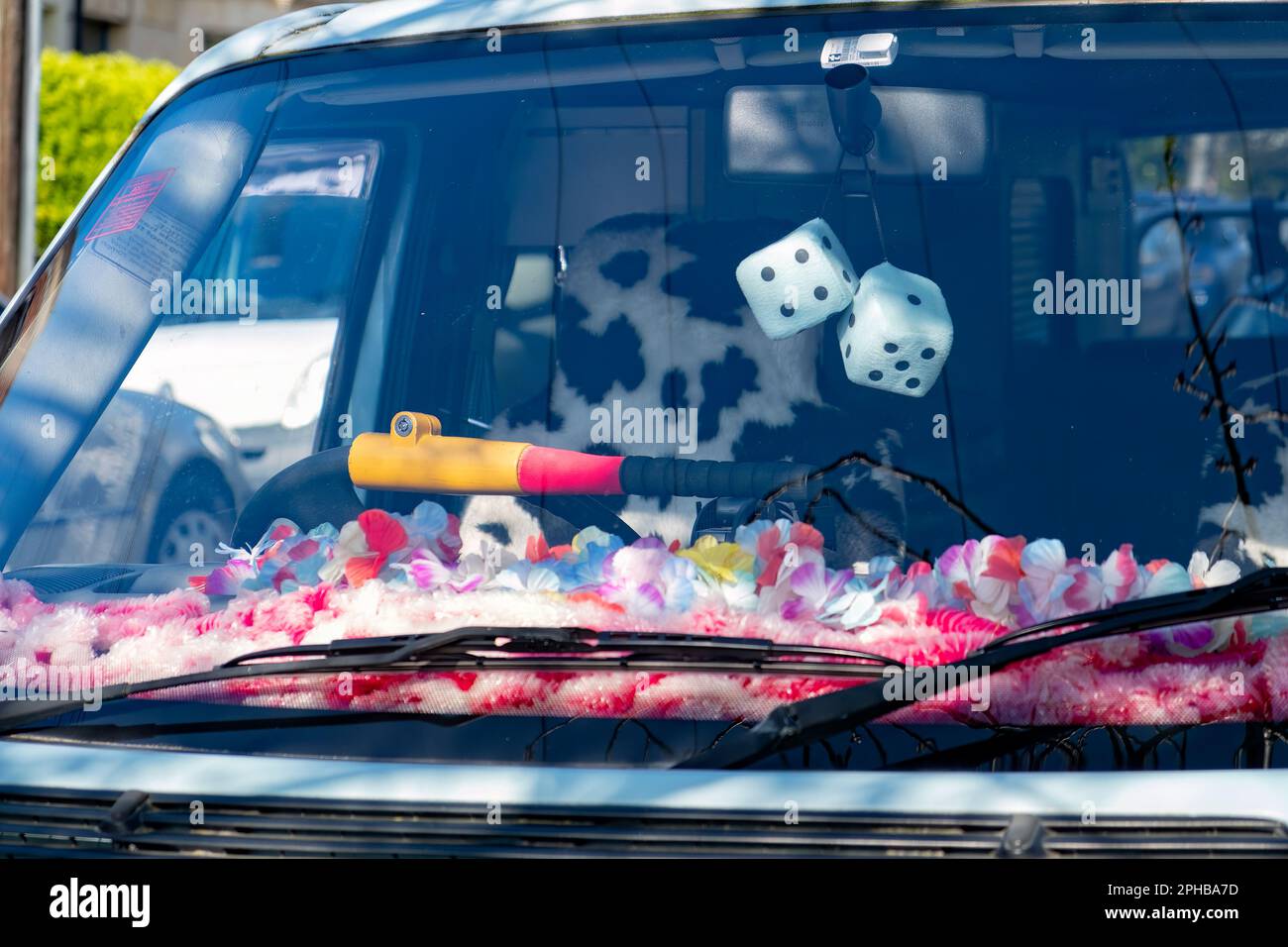 A close up of the front of a camper van showing a decorated dashboard, fur seat covers and two furry fluffy dice hanging from the rear view mirror Stock Photo