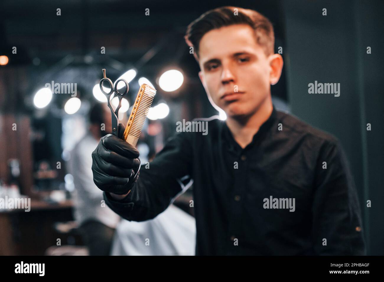 Portrait of young guy in black clothes that standing indoors in barber ...