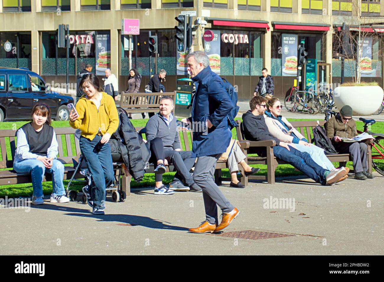 Glasgow, Scotland, UK 27th March, 2023. UK Weather: Sunny in the city centre afternoon saw the locals take to the streets. Fun in george square where witherspoons have been granted leave for permament outside tables for their 'the counting house' pub to give it a more continrntal feel. Credit Gerard Ferry/Alamy Live News Stock Photo