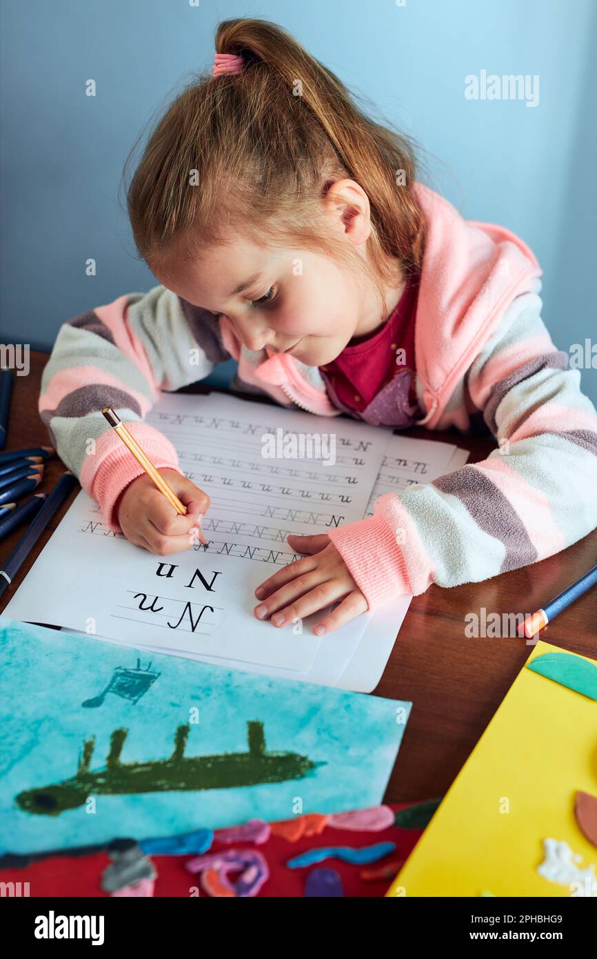 Little girl preschooler learning to write letters at home kid using