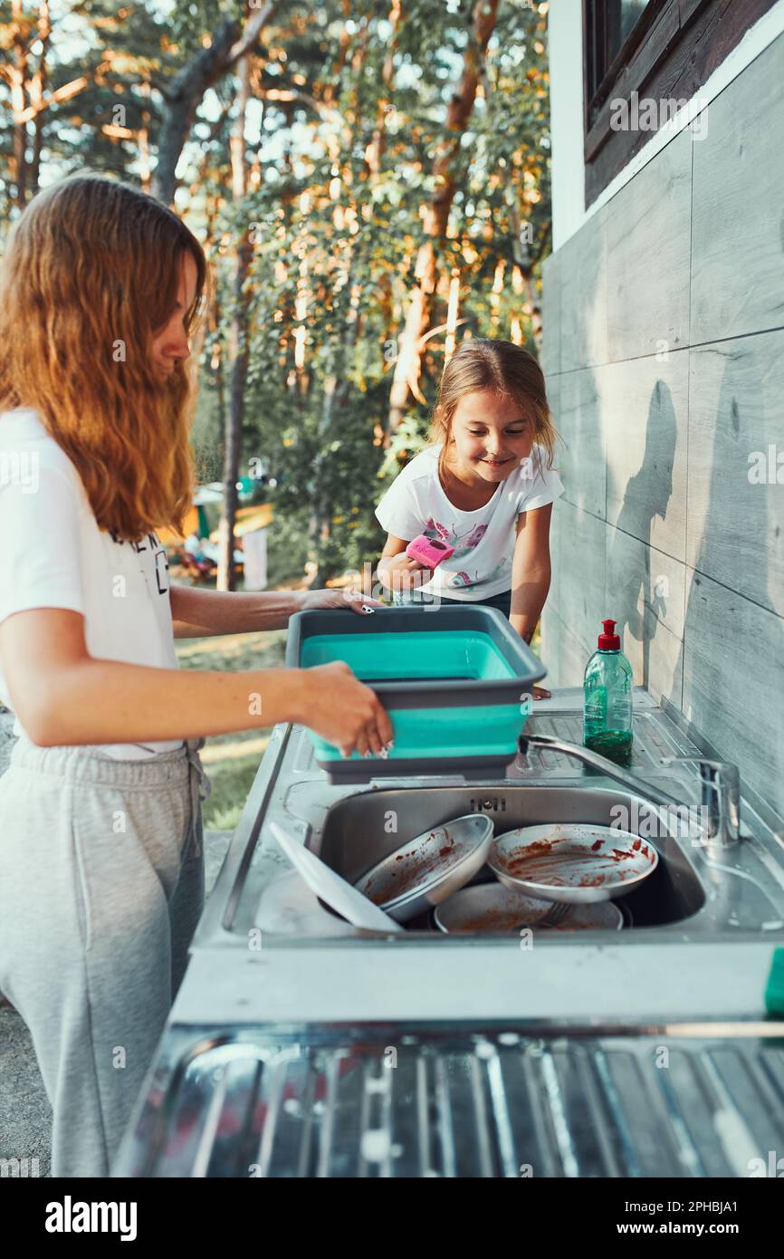Teenager girl washing up the dishes pots and plates with help her