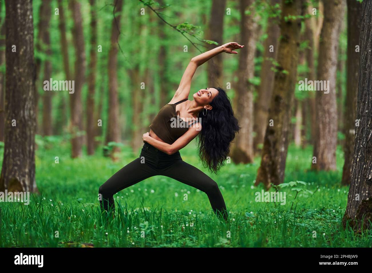 Positive brunette doing fitness outdoors in the forest at daytime Stock ...