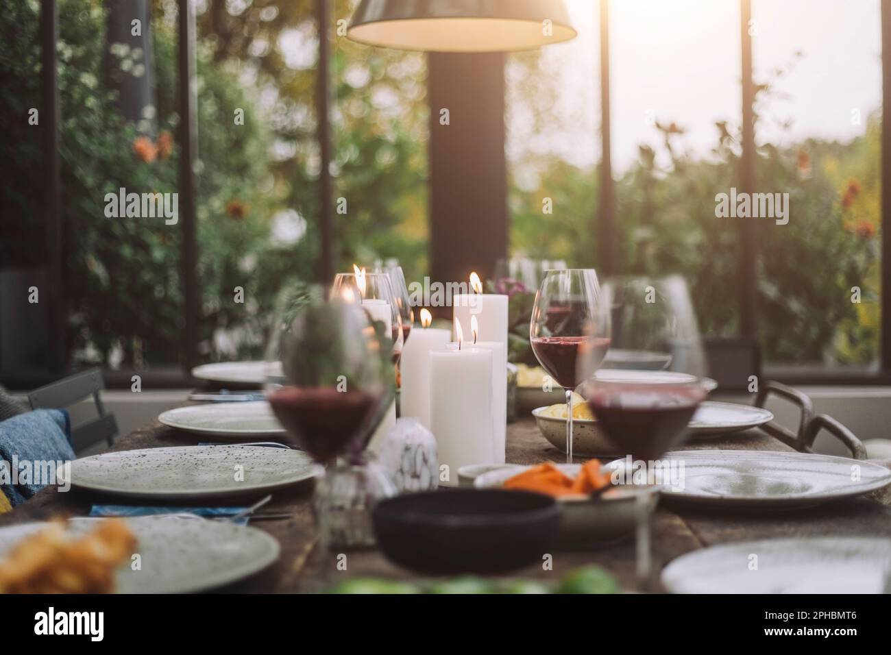 Illuminated candles with wineglasses on dining table Stock Photo