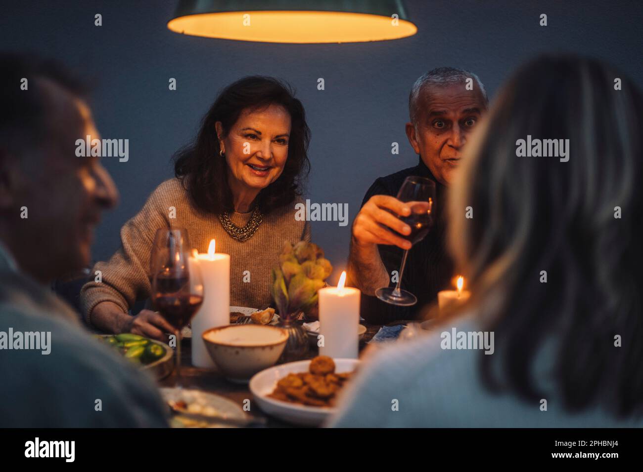 Smiling retired woman enjoying dinner with friends at party Stock Photo