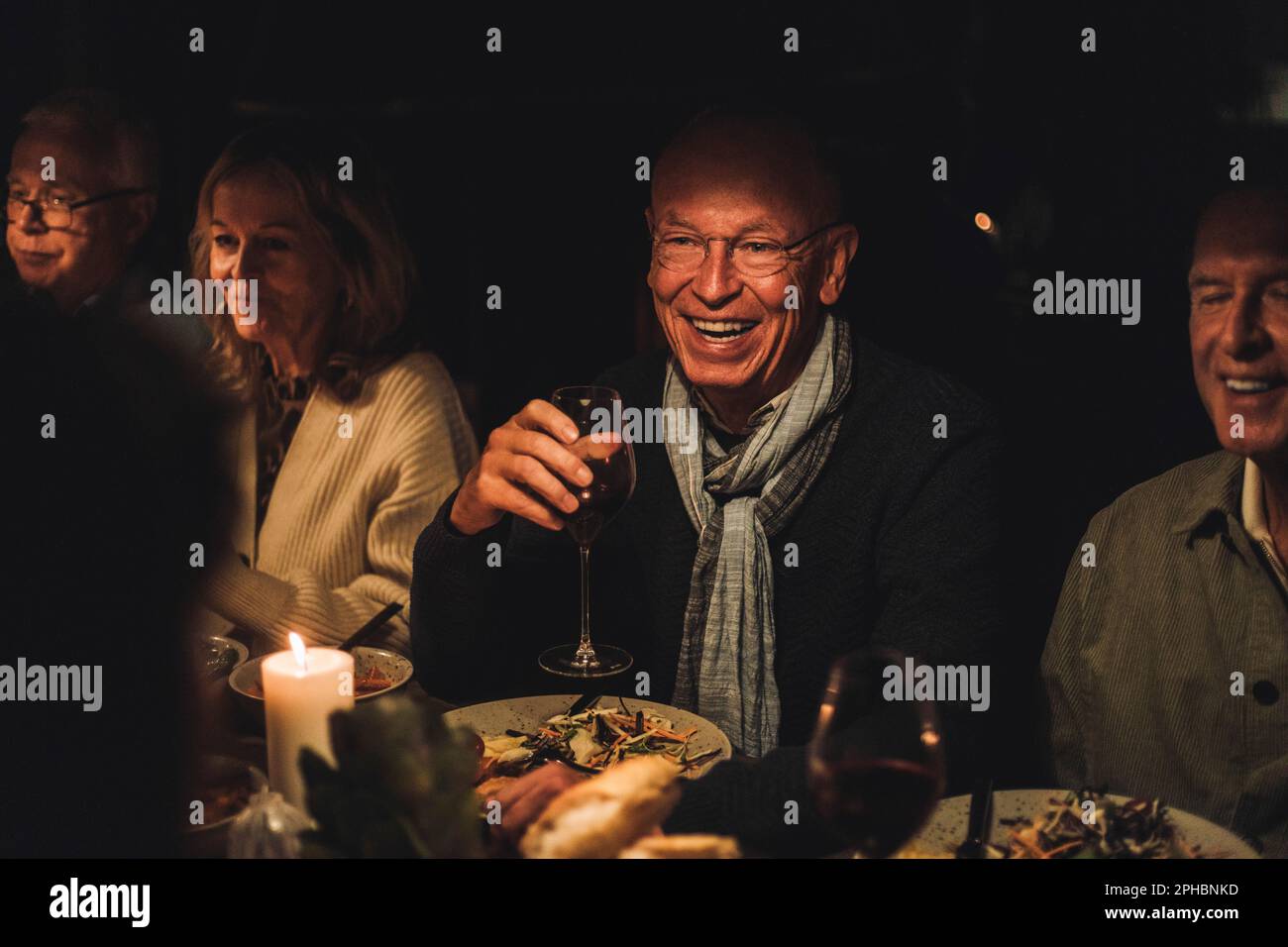 Happy senior man with friends during dinner party at night Stock Photo