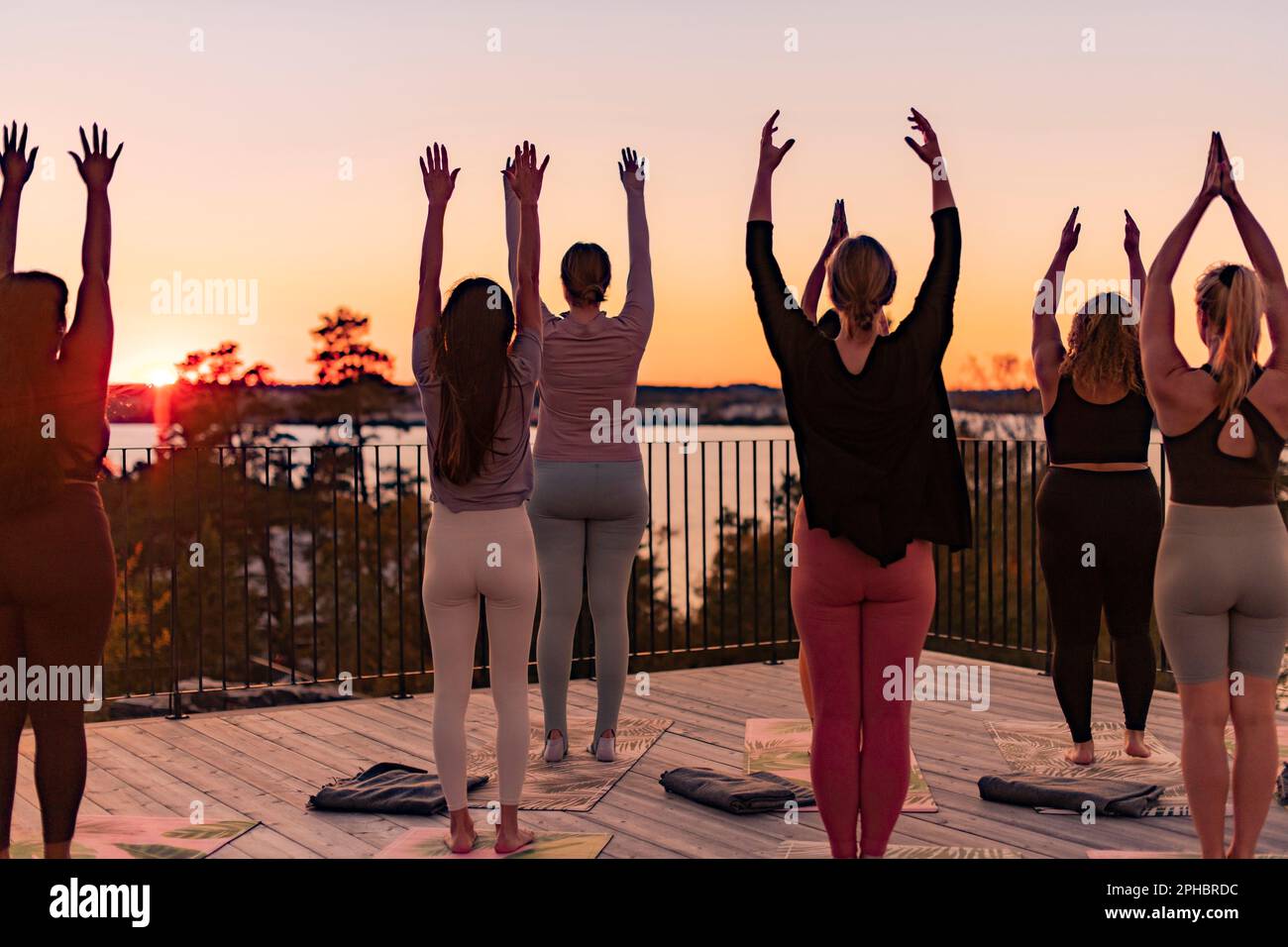 Rear view of female friends standing with arms raised on patio at retreat center Stock Photo