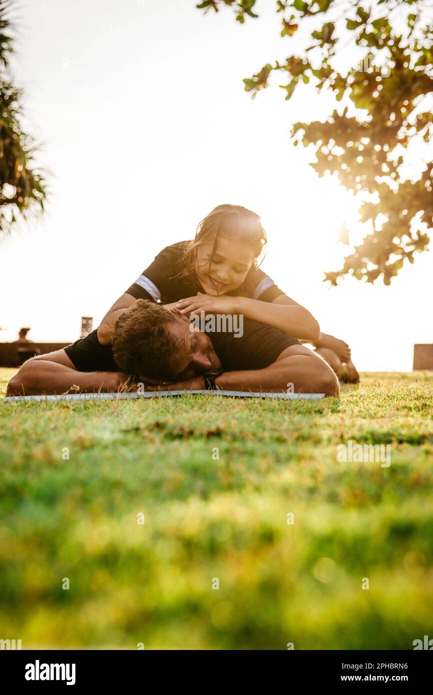 Tired man with daughter on back after exercising in park during sunset Stock Photo
