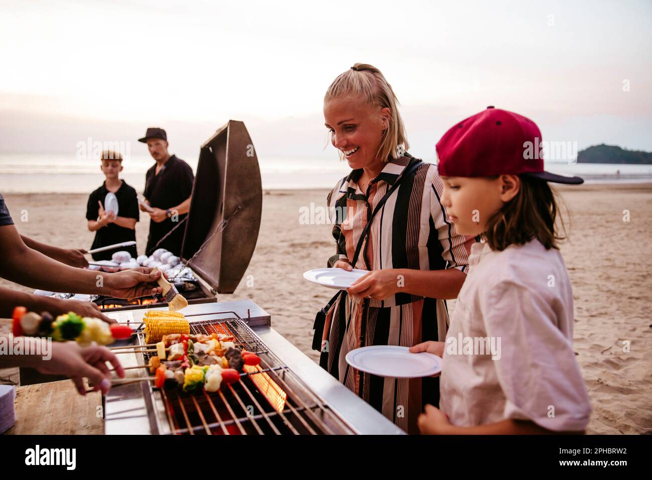 Mother and daughter standing near barbecue grill while holding plates ...