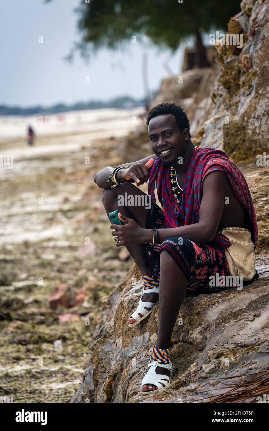 A handsome Tanzanian man is pictured atop a rocky outcrop on a sandy ...