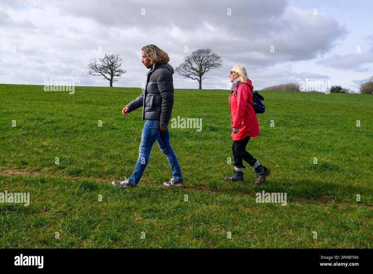 Man and woman walking across a field, walking in a field, man in front Stock Photo