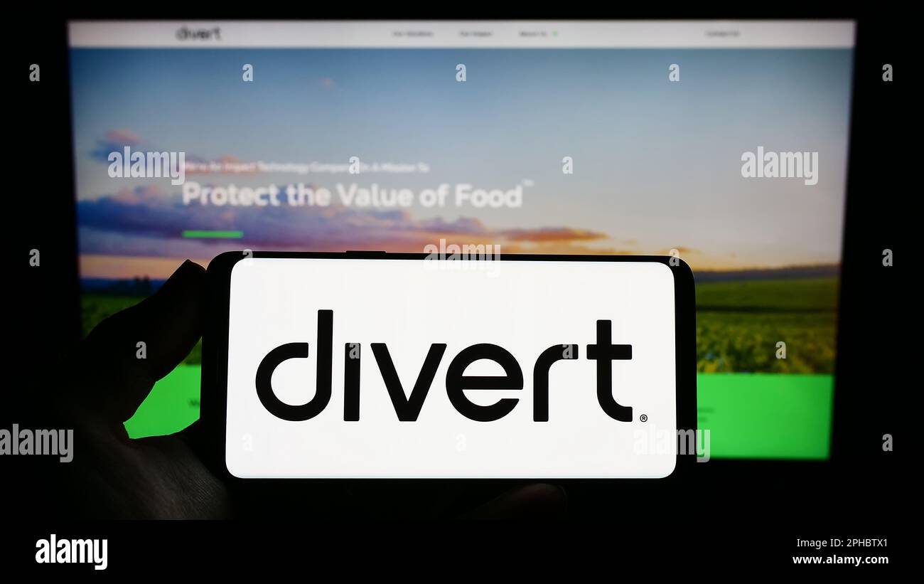 Person holding smartphone with logo of US food technology company Divert Inc. on screen in front of website. Focus on phone display. Stock Photo