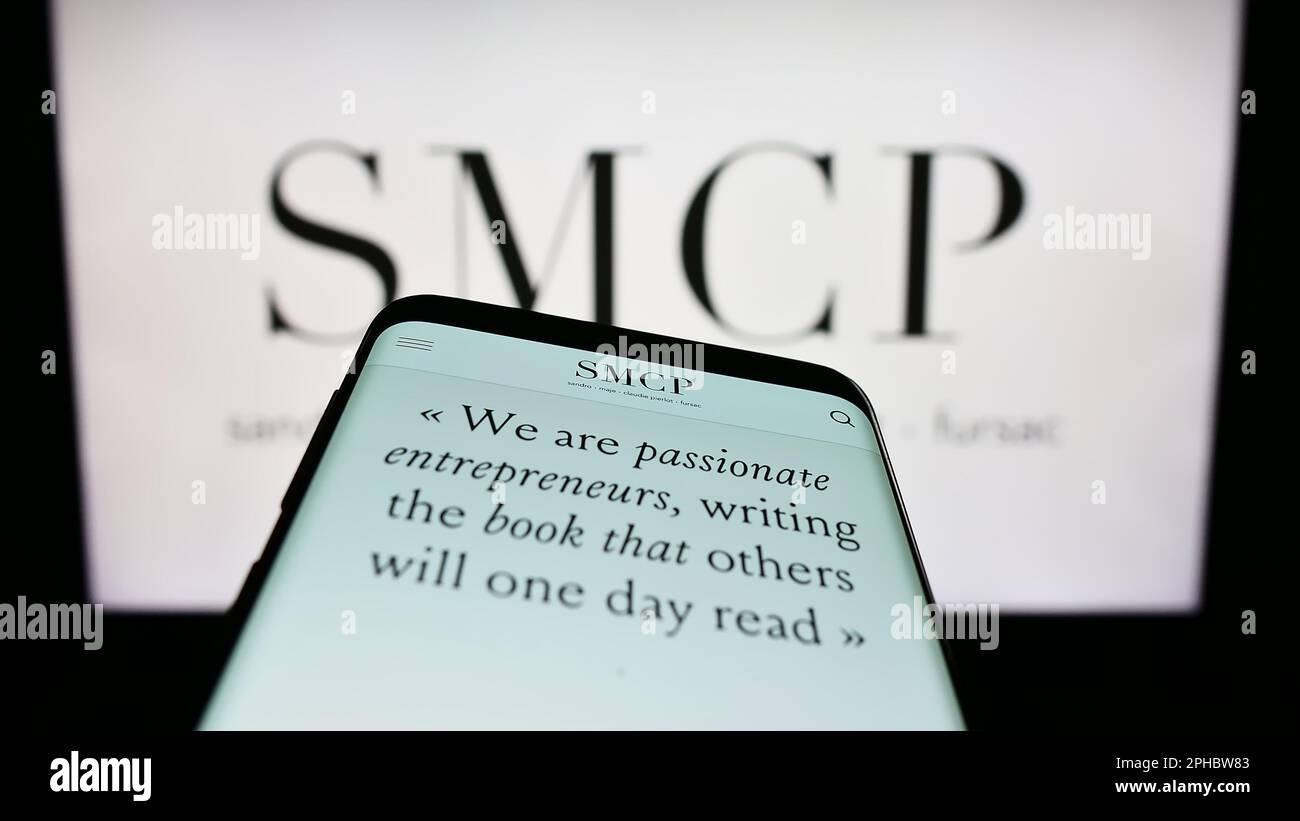 Mobile phone with website of French luxury fashion company SMCP S.A. on screen in front of business logo. Focus on top-left of phone display. Stock Photo