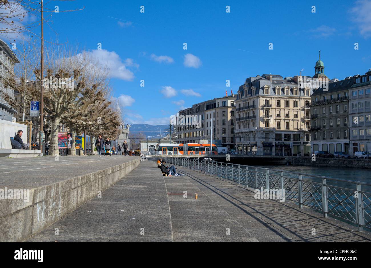 People hanging by the banks of the Rhone river during the winter. Blue skies in Geneva Stock Photo