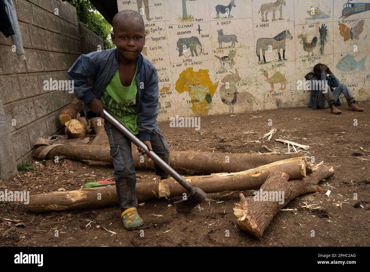 Arusha, Tanzania - October 17th, 2022: A boy splitting wood in the Fruitful Orphanage in Arusha, Tanzania. Stock Photo