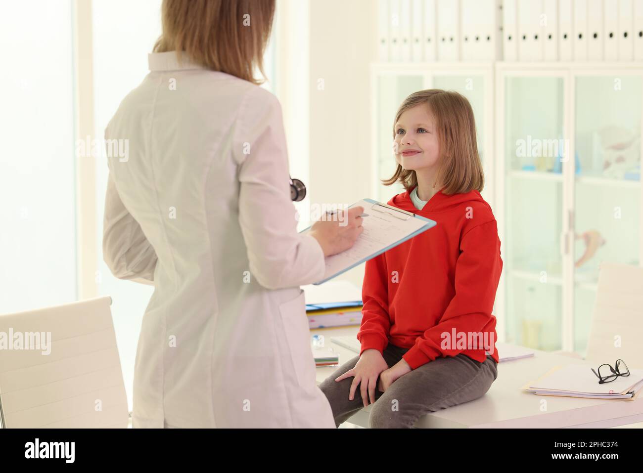Doctor with clipboard examines little girl in hospital Stock Photo