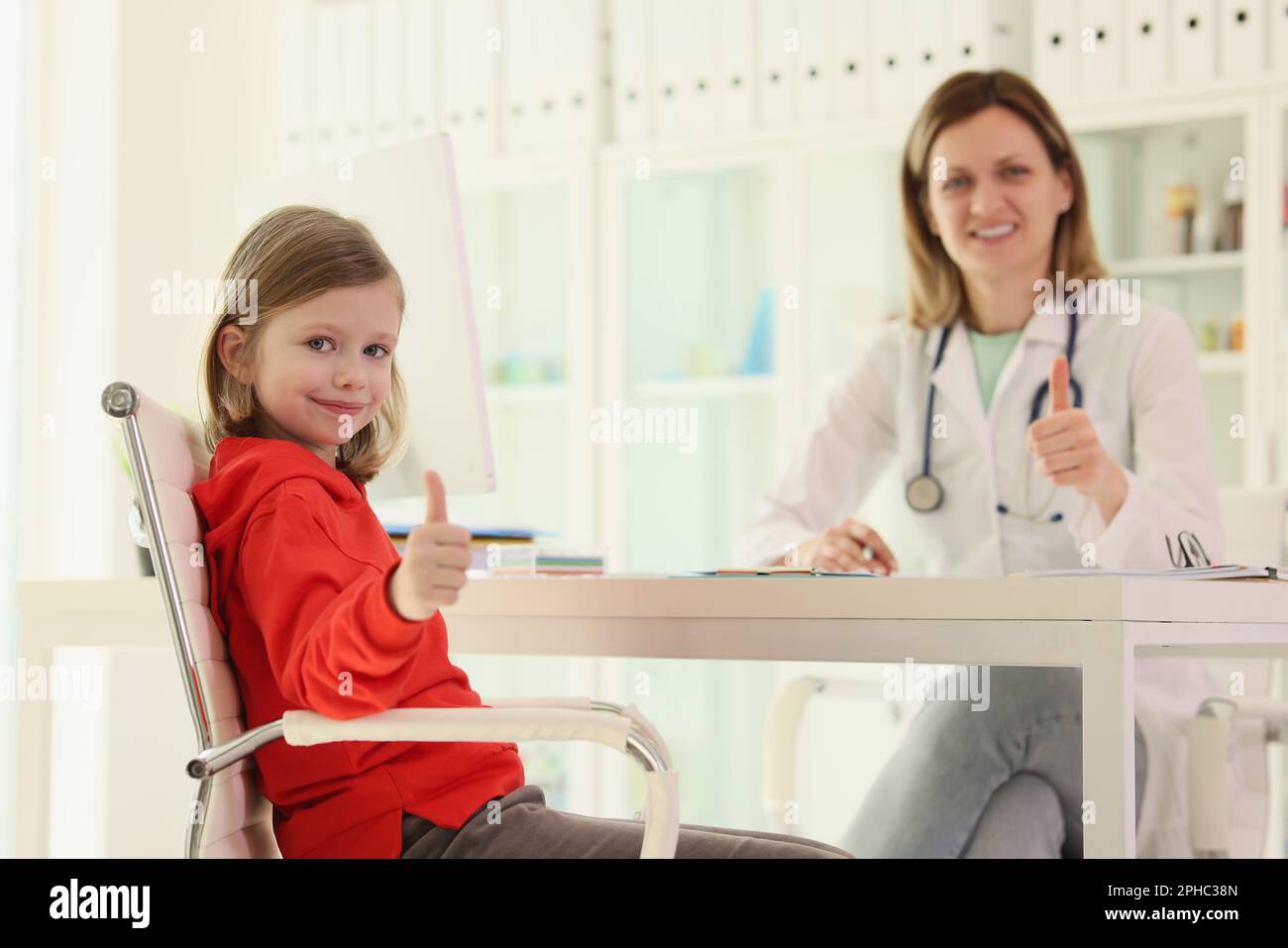 Little girl and doctor shows thumbs up at appointment Stock Photo