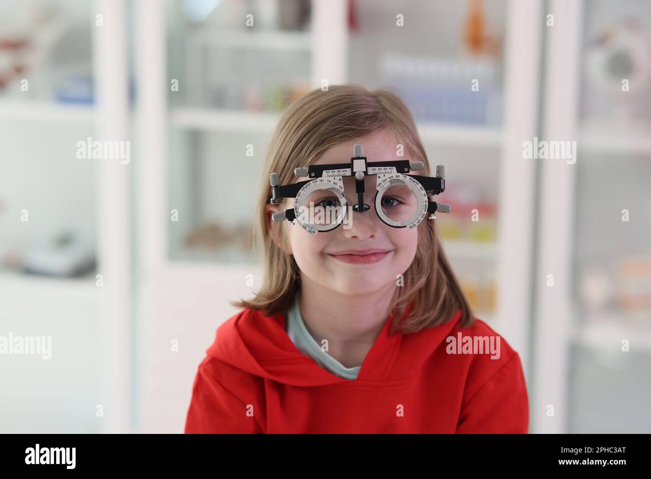 Girl with eye examining tool at ophthalmologist appointment Stock Photo