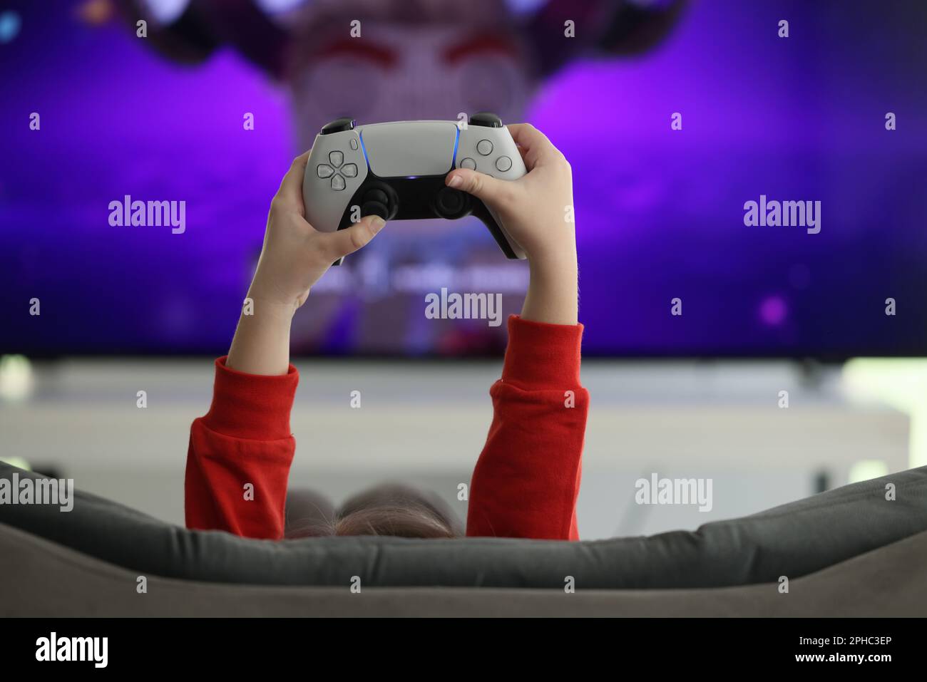 Hands of little girl holding game console against screen Stock Photo