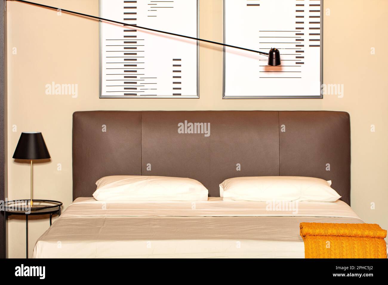 A double bed with a soft leather headboard, abstract wall art and a