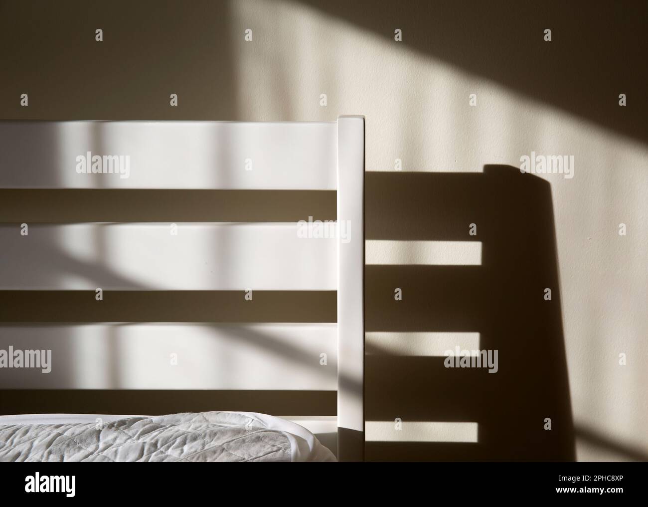 Bed Headboard Lit by Morning Sunshine Stock Photo
