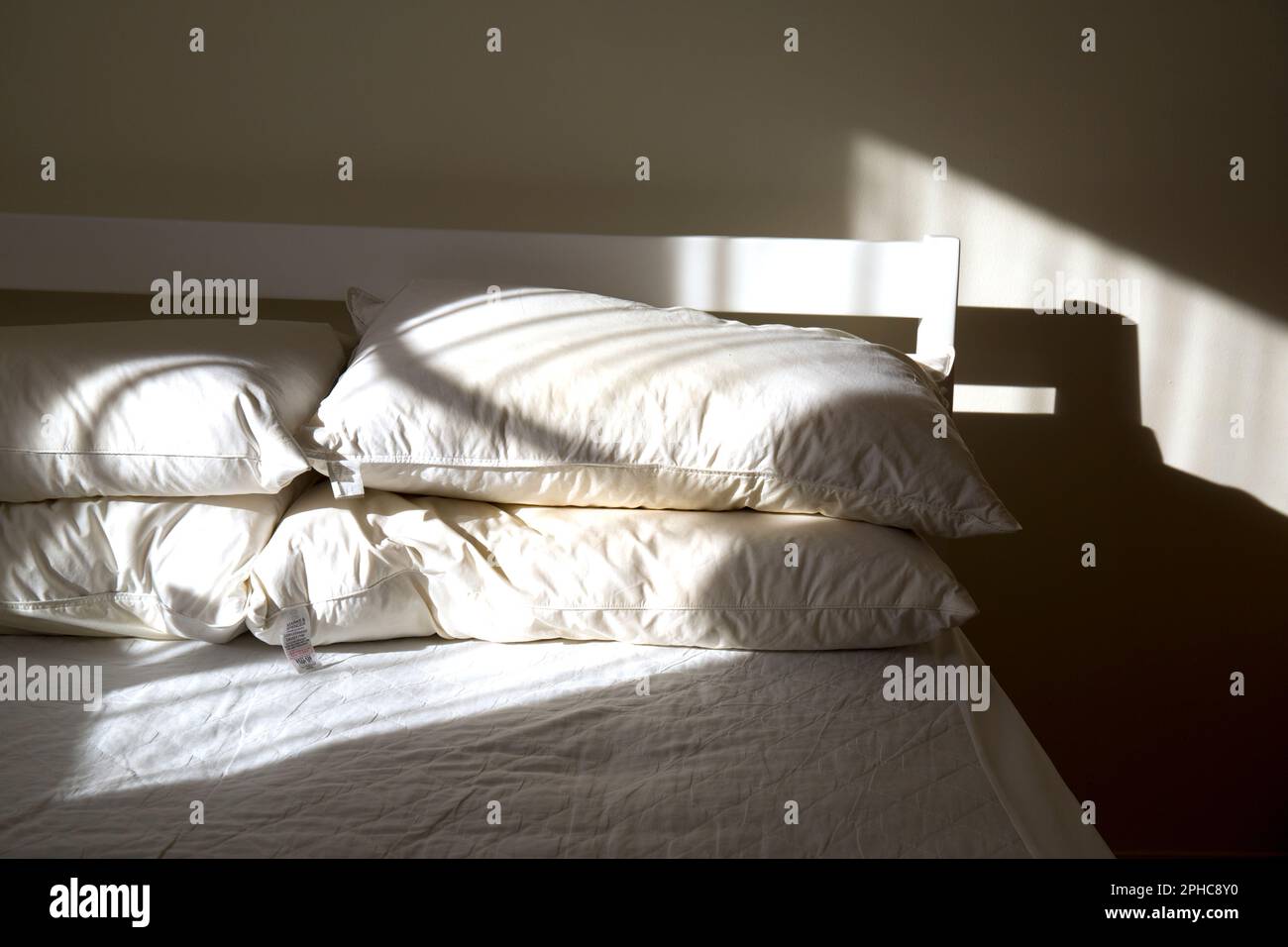 Unmade Bed Lit by Morning Sunshine Stock Photo