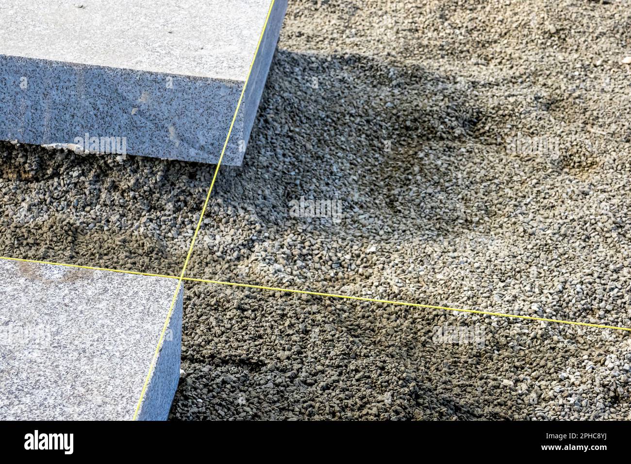 A yellow nylon string marking the alignment for accurately laid solid  granite blocks on the gravel surface of a construction site Stock Photo -  Alamy