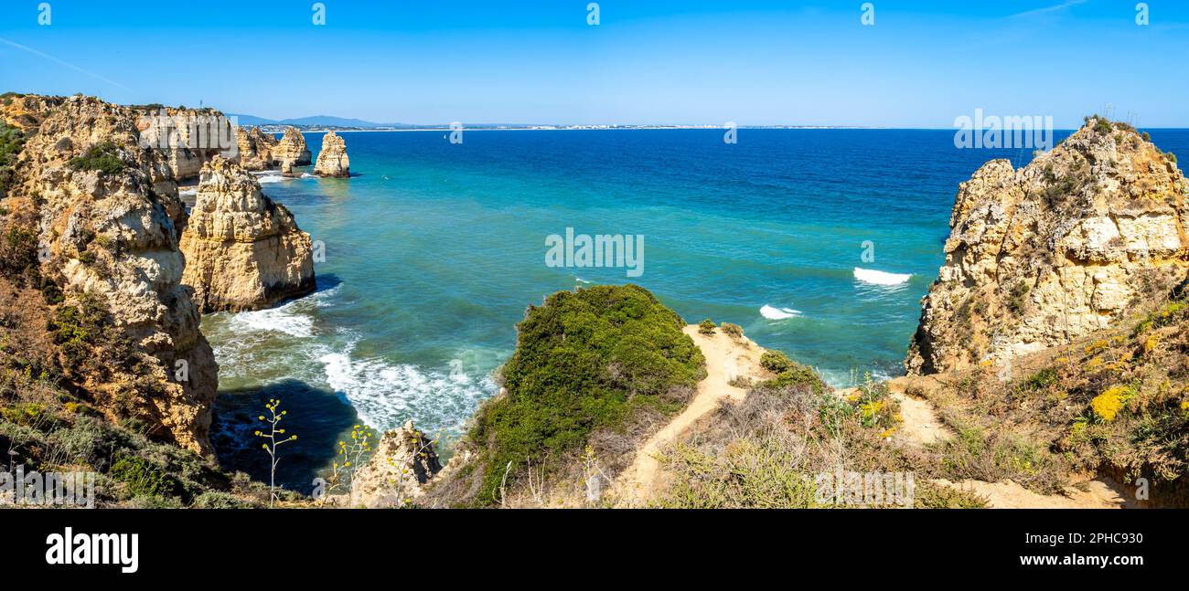 Wide-angle view from Miradouro da Ponta da Piedade captures the rugged, rocky coastline of the Algarve with calm waters stretching to Portimao. Stock Photo