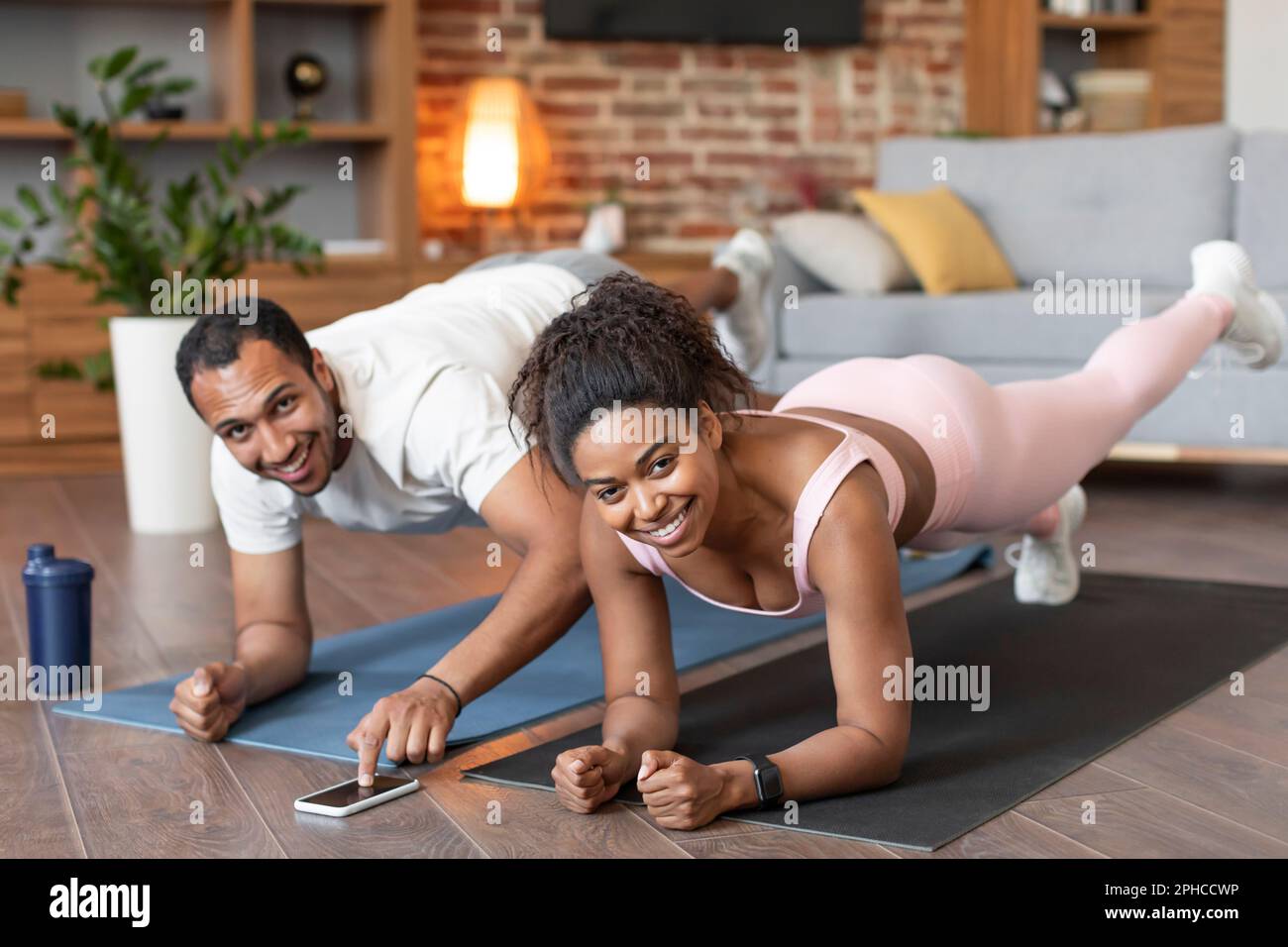 Body care new normal at home. Happy young black lady and guy in sportswear do leg exercises on floor Stock Photo Alamy