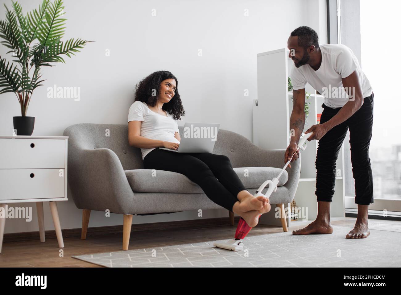 Smiling african american woman sitting on couch and working on portable ...