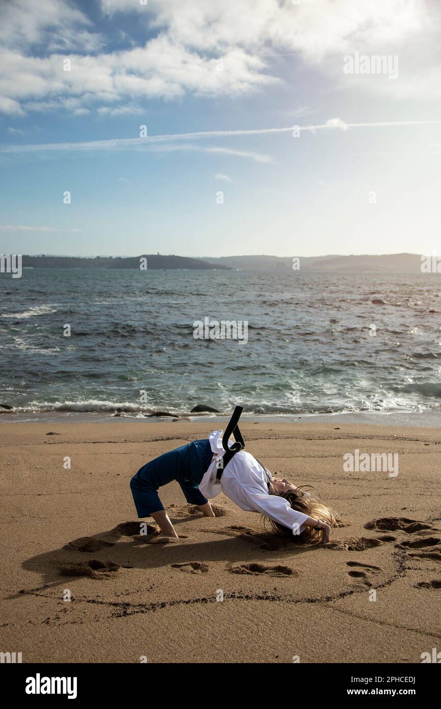doing bridge handstand on the beach wearing taekwondo clothes Stock