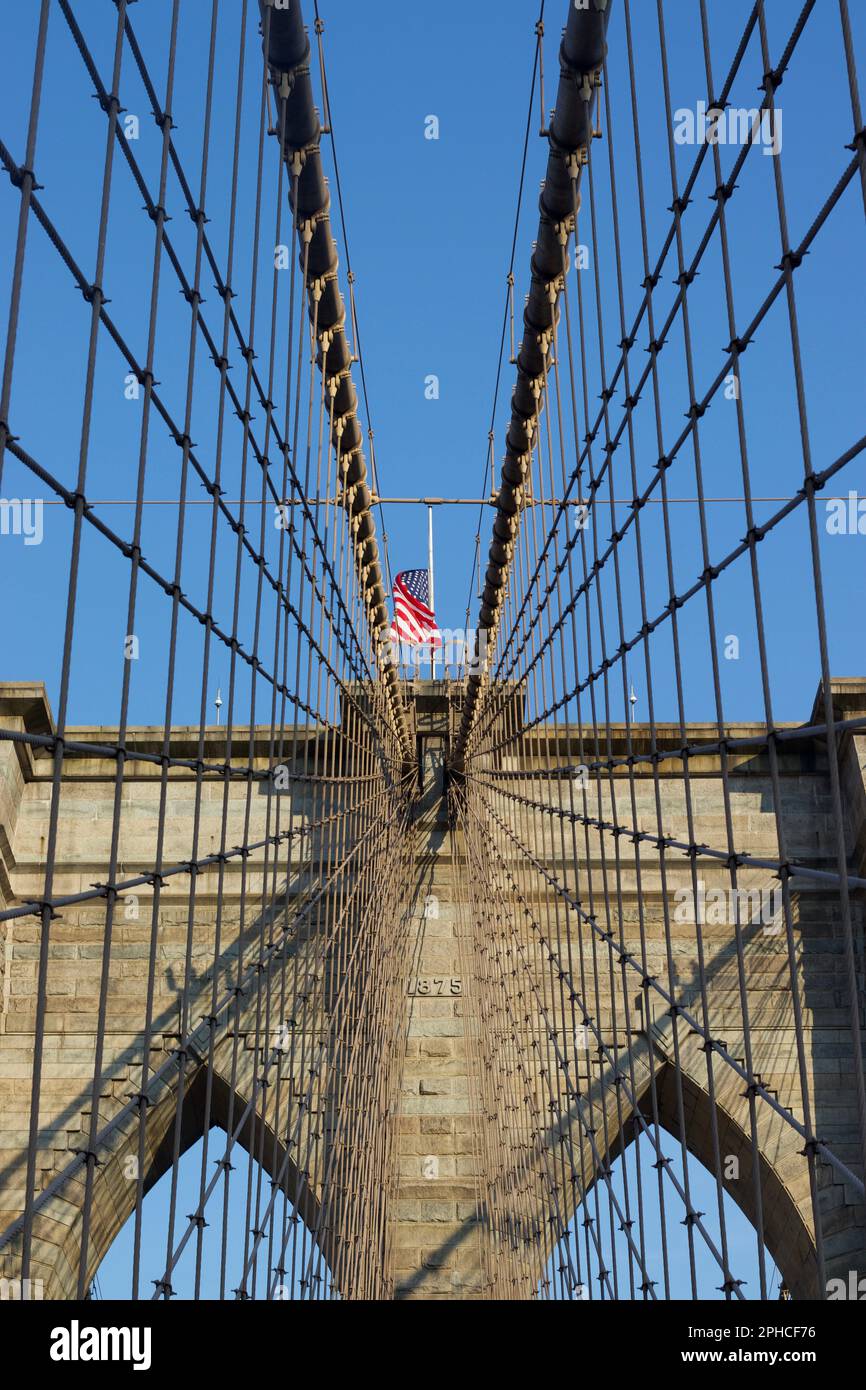 An American flag waving atop the iconic Brooklyn Bridge located in New York City Stock Photo