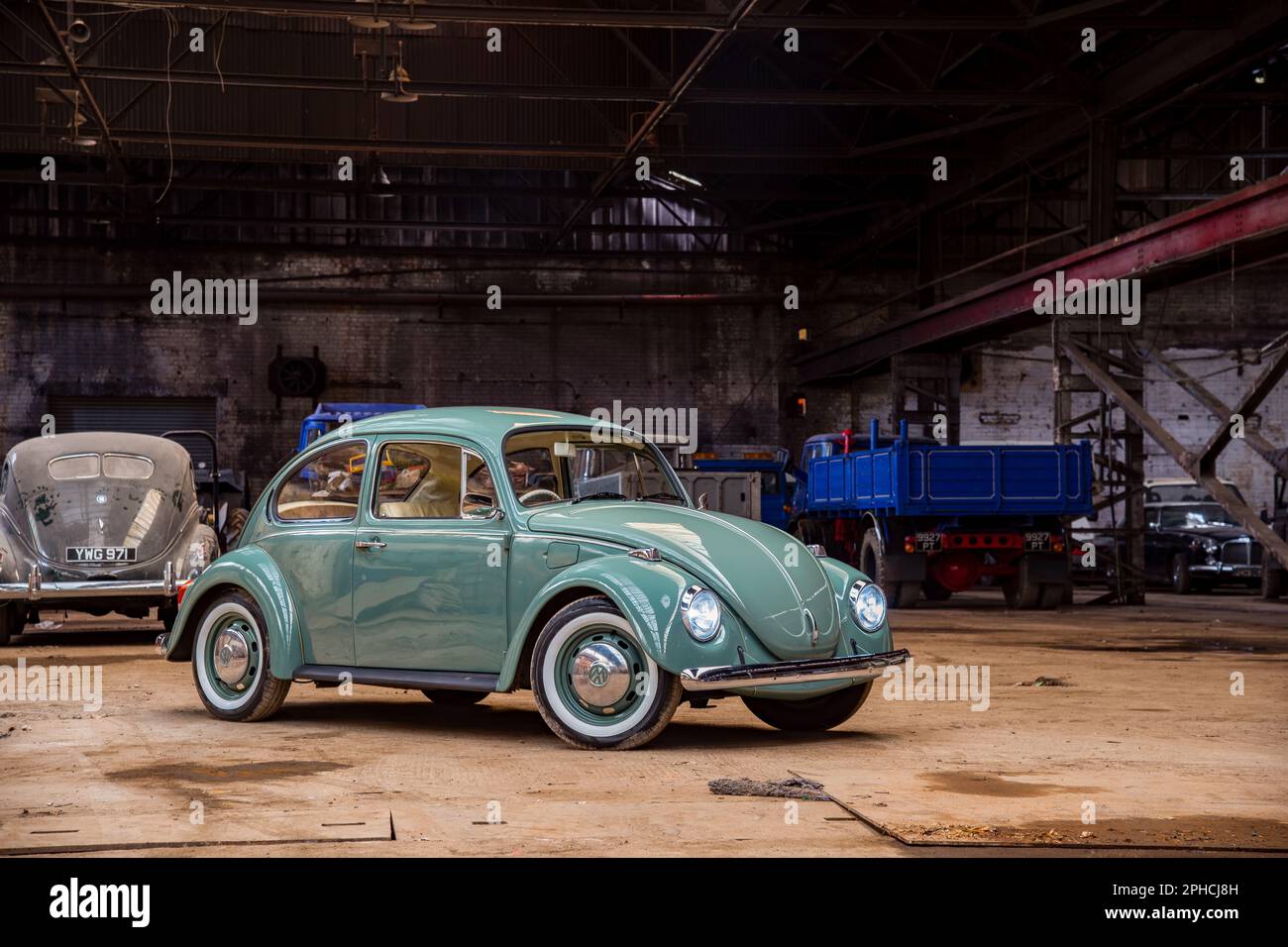 Green Volvkswagen Beetle with white walled tyres parked in an old engineering works Stock Photo