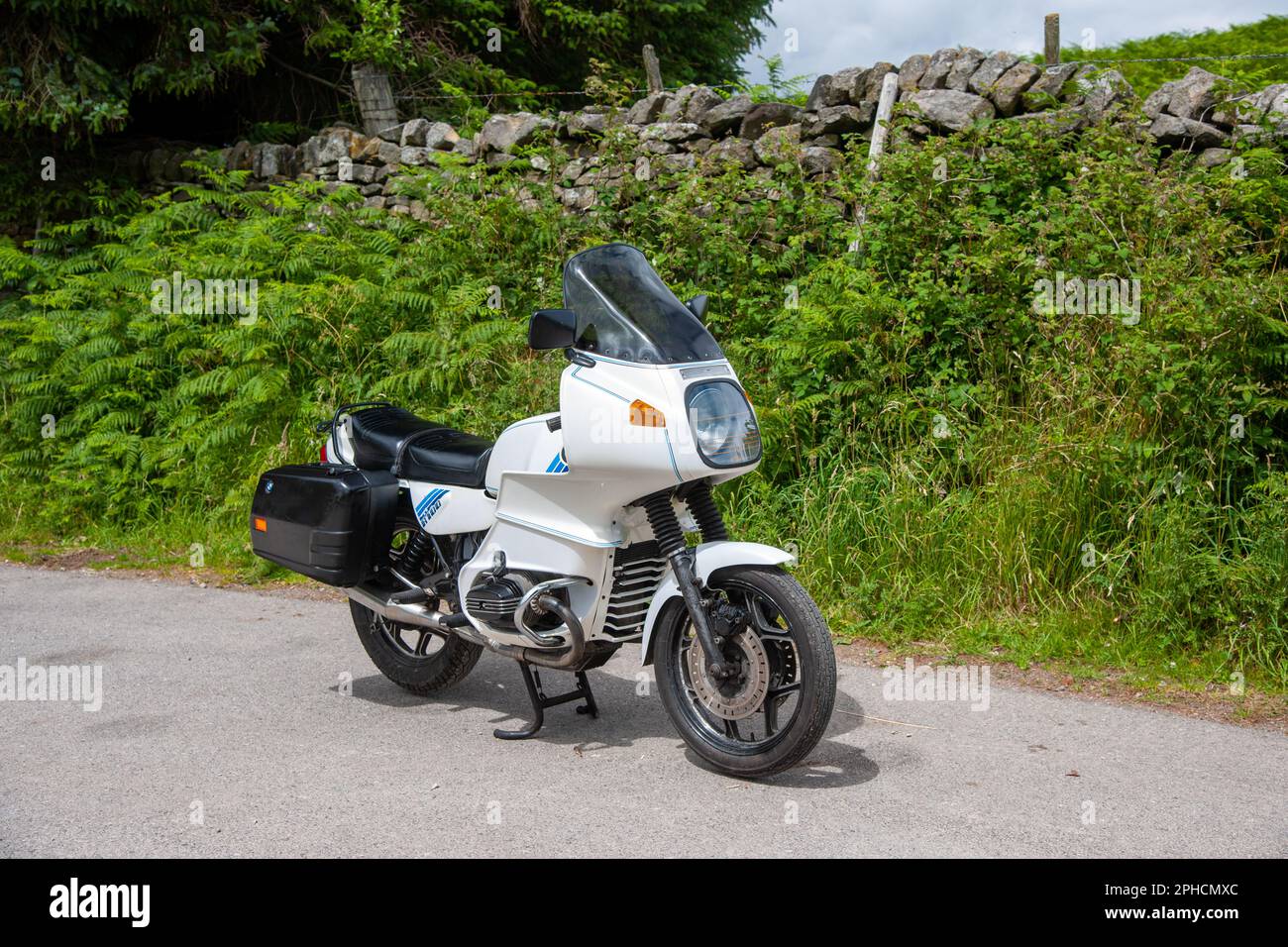 BMW R100 RS touring motocycle parked on a narrow country lane next to ferns and a dry stone wall in the Derbyshore Peak District Stock Photo