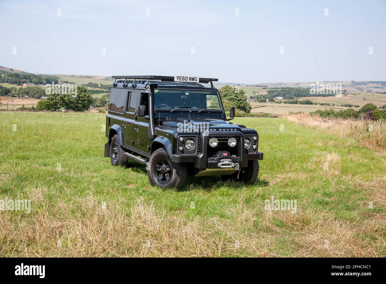 Black Land Rover Defender 110 long wheelbase parked in a field in Yorkshire on a sunny Summer day Stock Photo