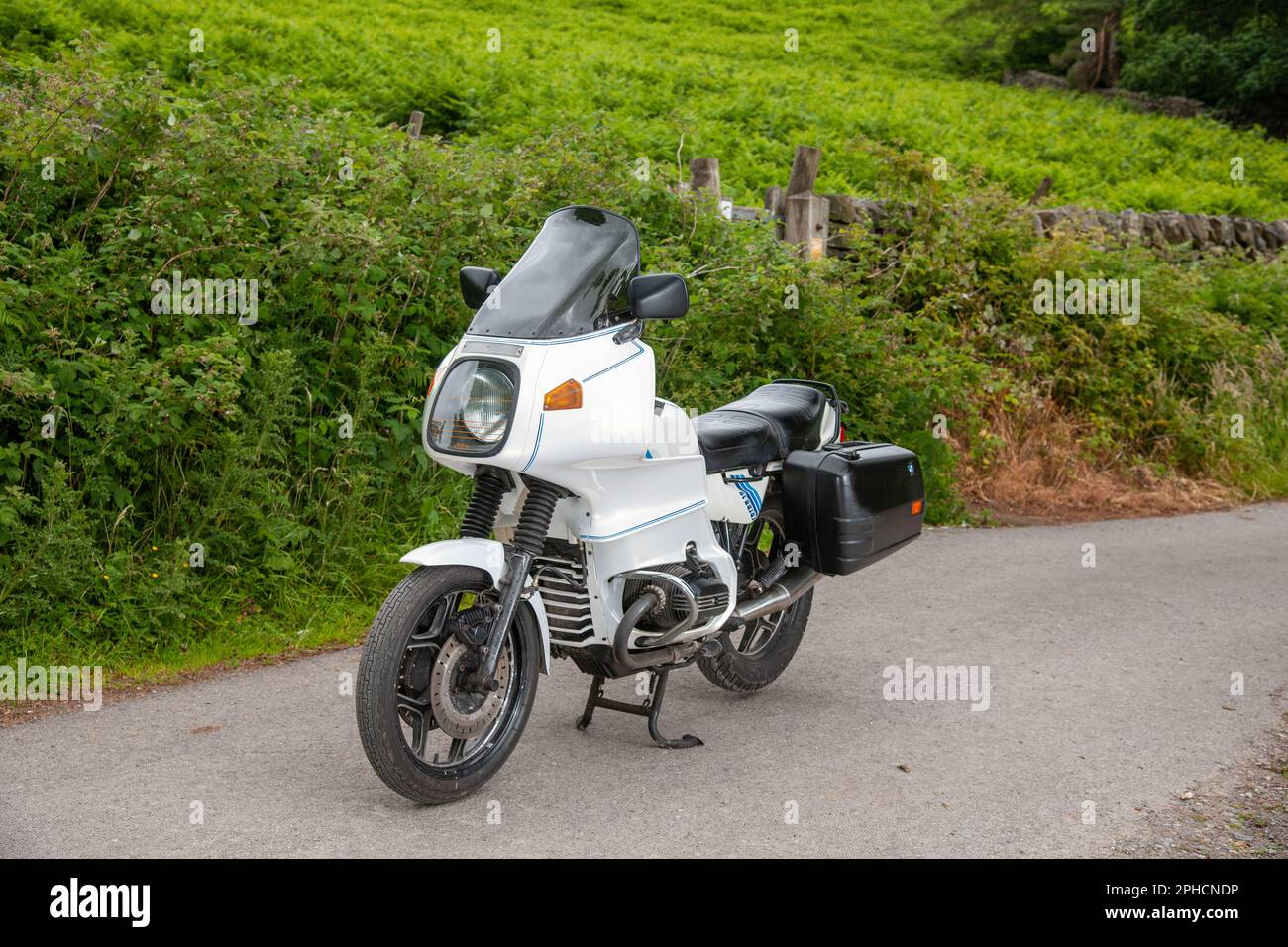 BMW R100 RS touring motocycle parked on a narrow country lane next to ferns and a dry stone wall in the Derbyshore Peak District Stock Photo