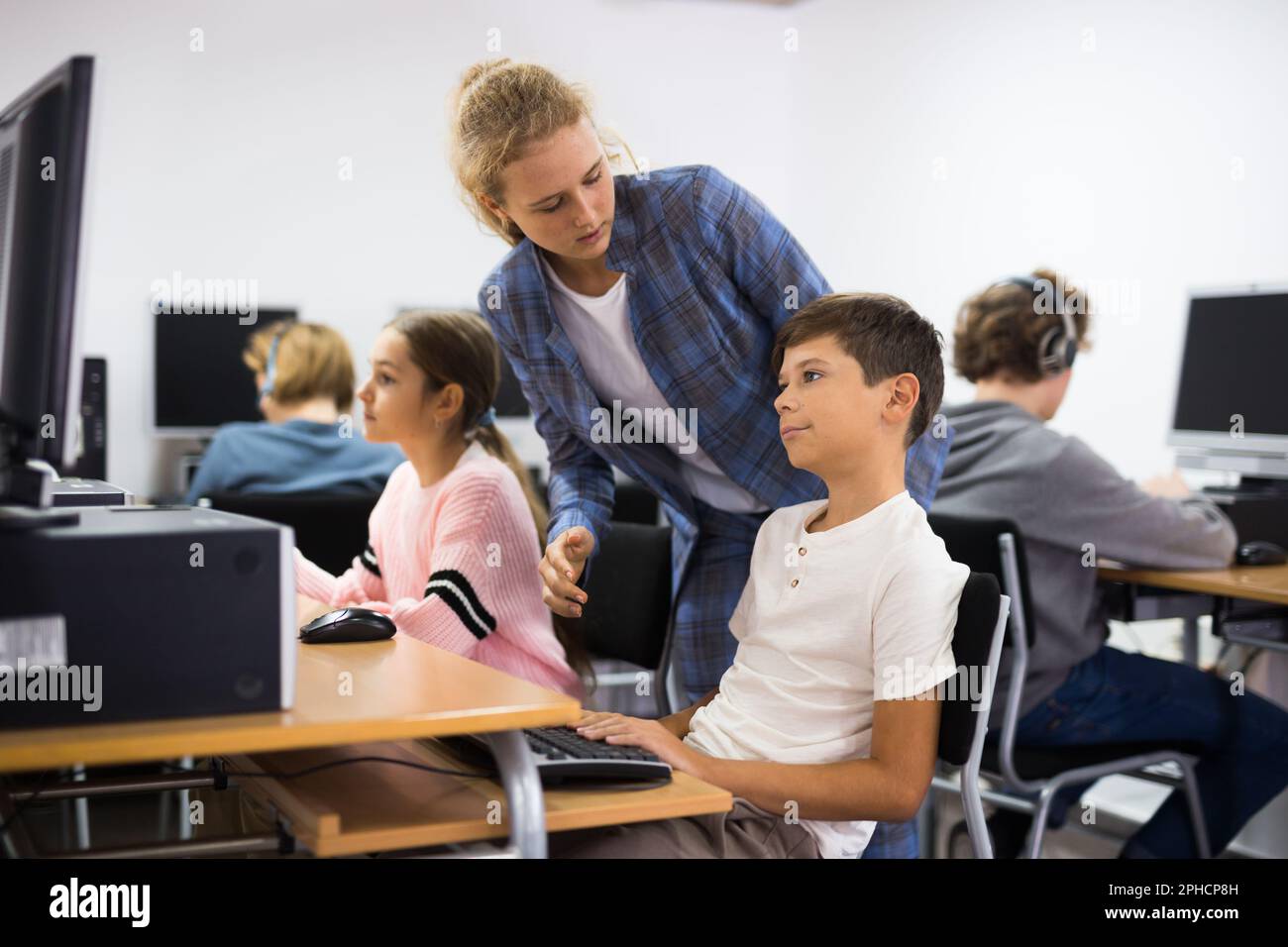 Girl helping boy with computer problem Stock Photo - Alamy