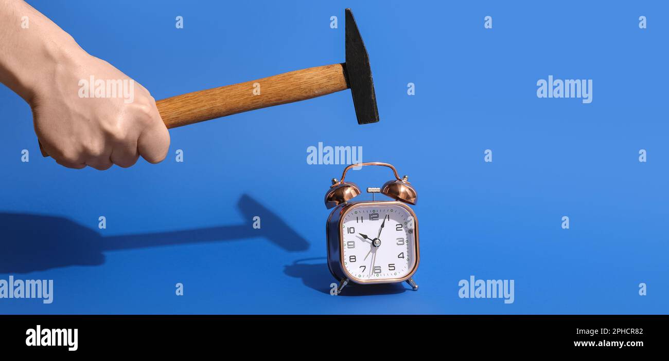 Human hand with hammer and alarm clock on blue background Stock Photo ...