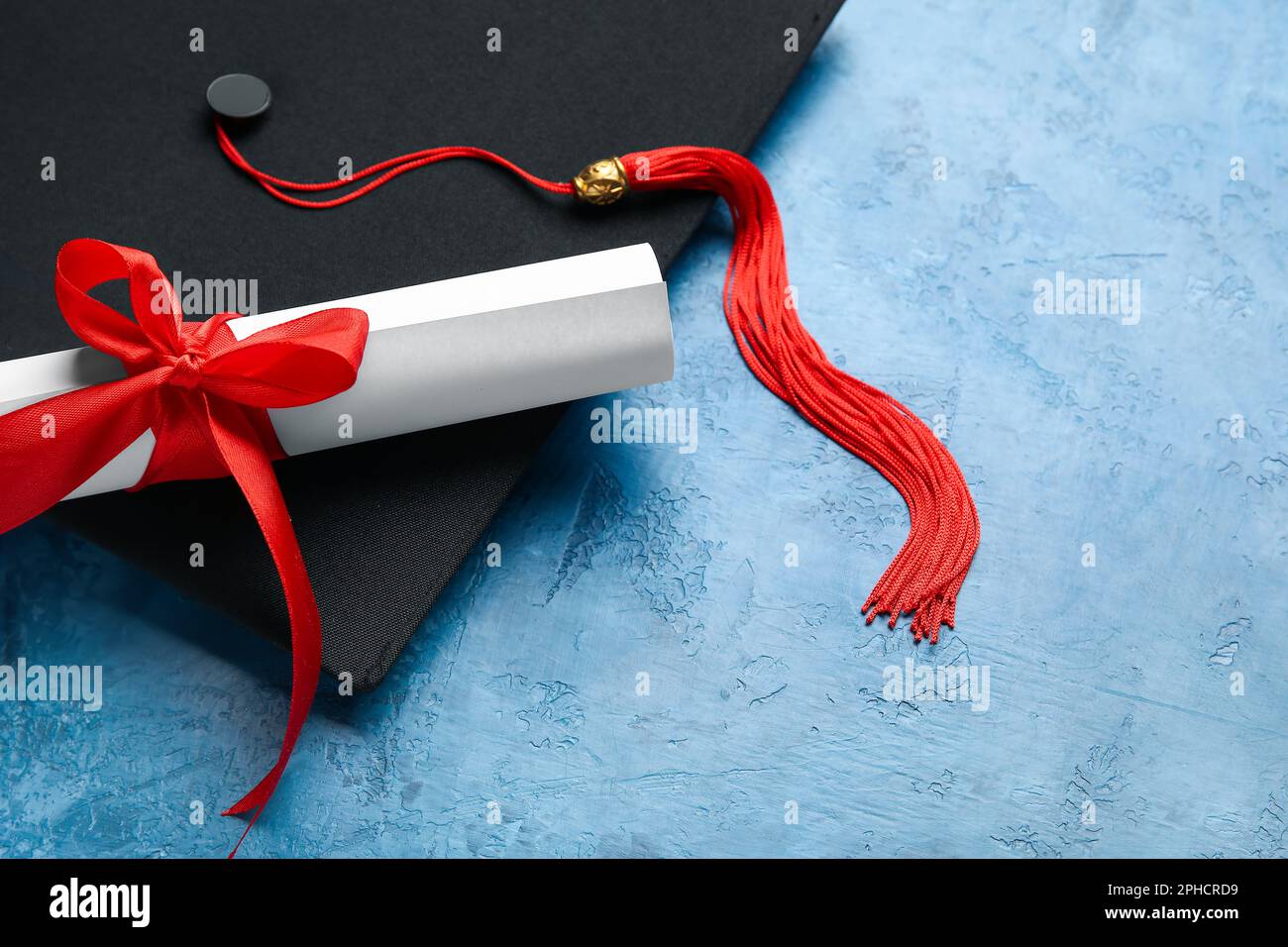 Diploma with red ribbon and graduation hat on blue table Stock Photo ...