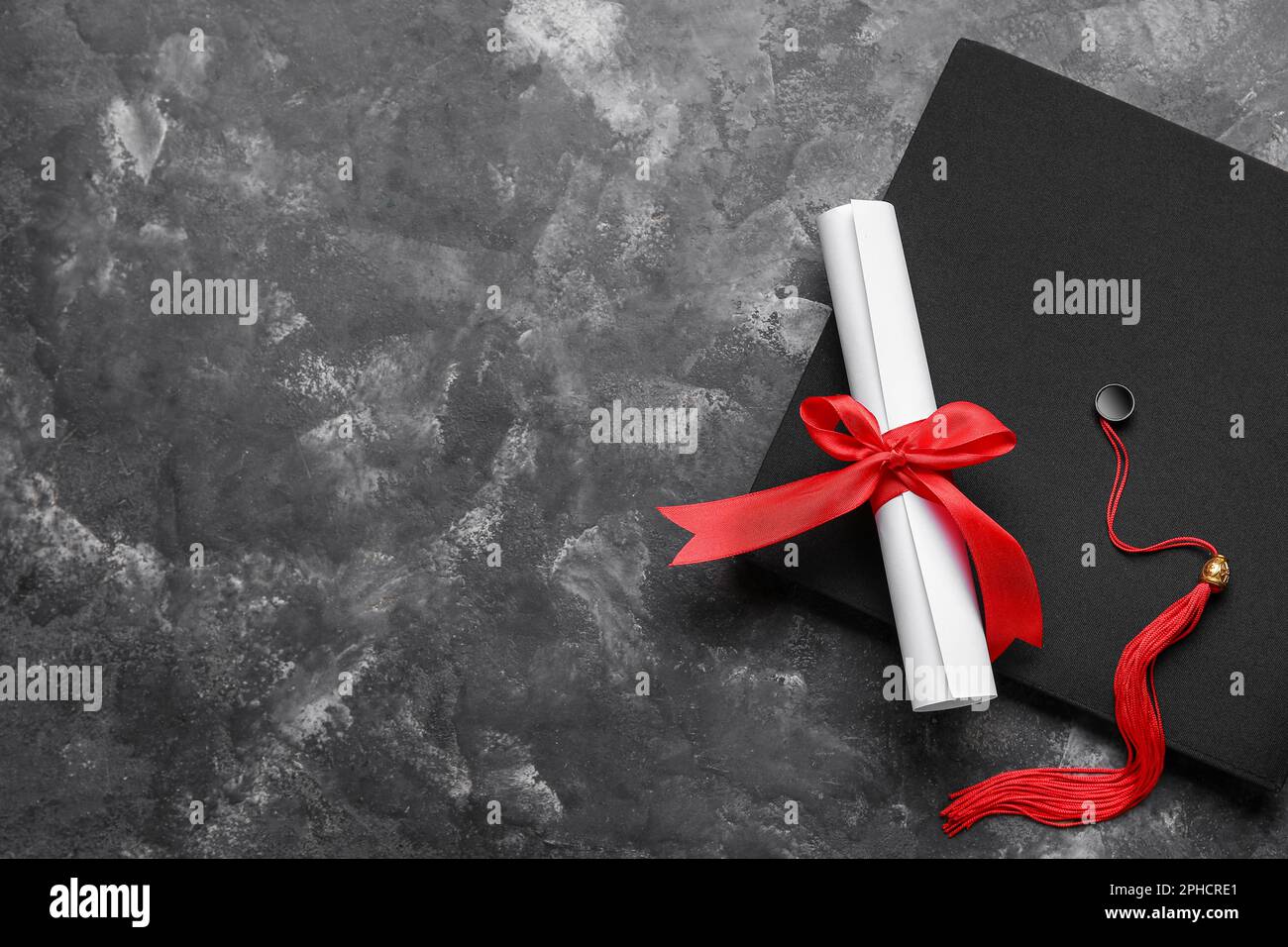 Red Ribbon Graduation Diploma with red ribbon and graduation hat on dark grey table Stock ...