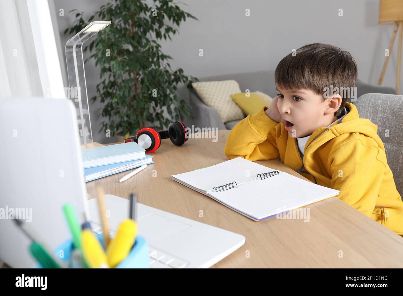 Cute little boy with modern laptop studying online at home. E-learning ...