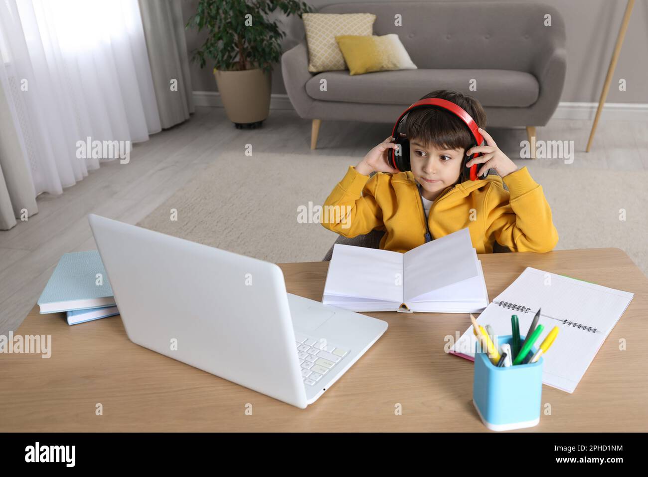 Cute little boy with modern laptop studying online at home. E-learning ...