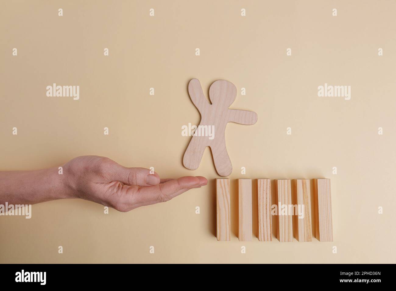 Woman holding hand to help human figure overcome abyss on beige background, closeup. Relationships, support and deal concepts Stock Photo