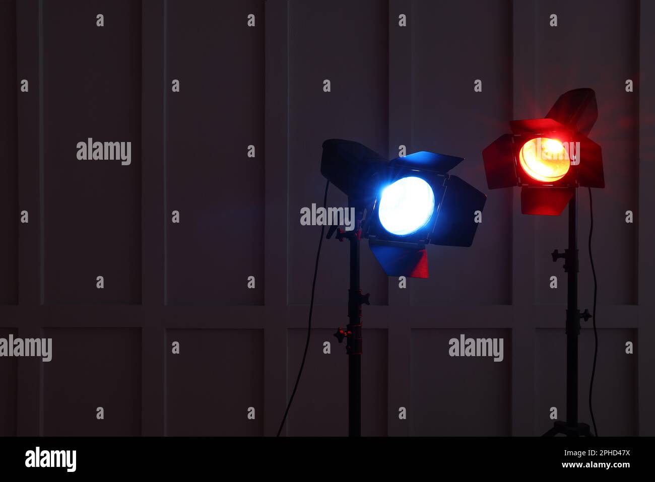 Bright red and blue spotlights near wall in dark room, space for text