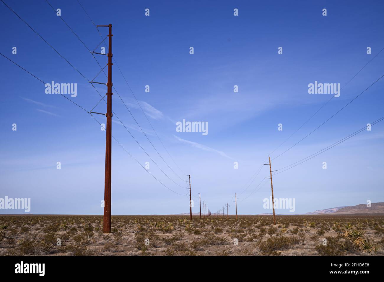 electric power lines in the desert with metal and wood poles Stock Photo