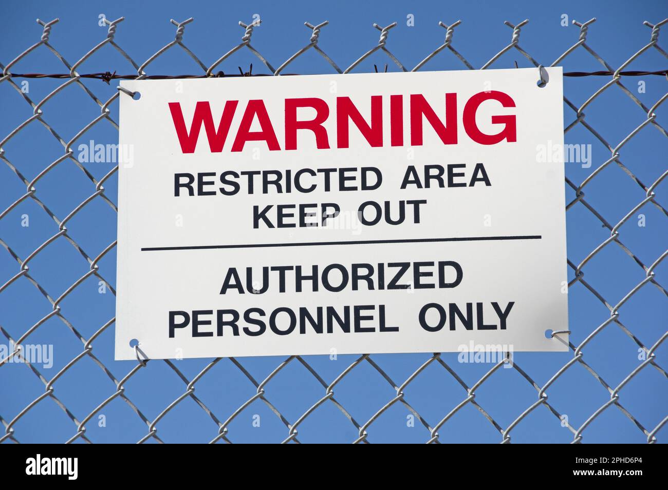 warning restricted area keep out authorized personnel only sign on a wire fence with blue sky background Stock Photo