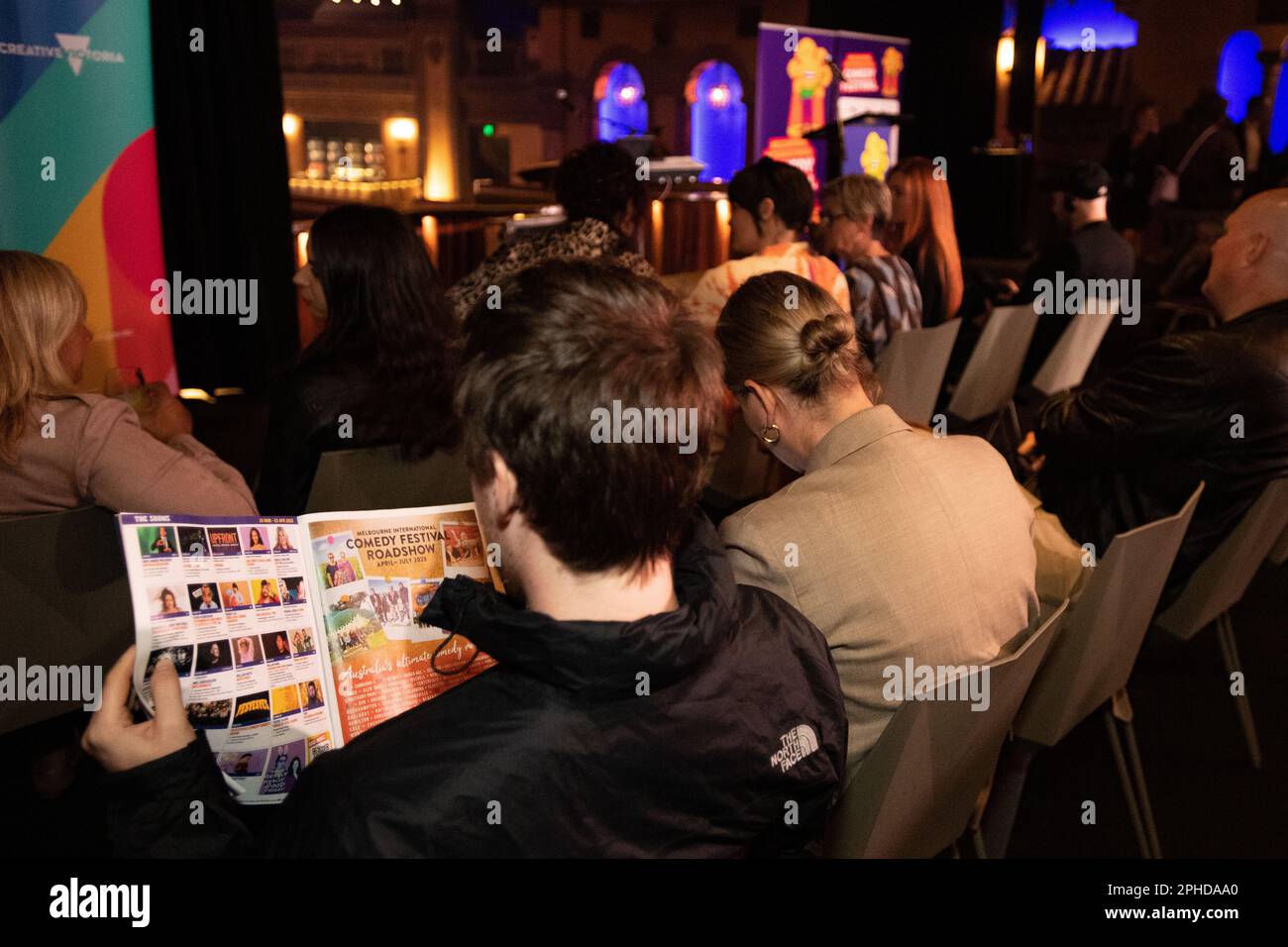 Melbourne, Australia, 28th March 2023. An attendee reads the schedule for the upcoming Melbourne International Comedy Festival at its launch at the Forum Melbourne. Credit: Jay Kogler/Alamy Live News Stock Photo